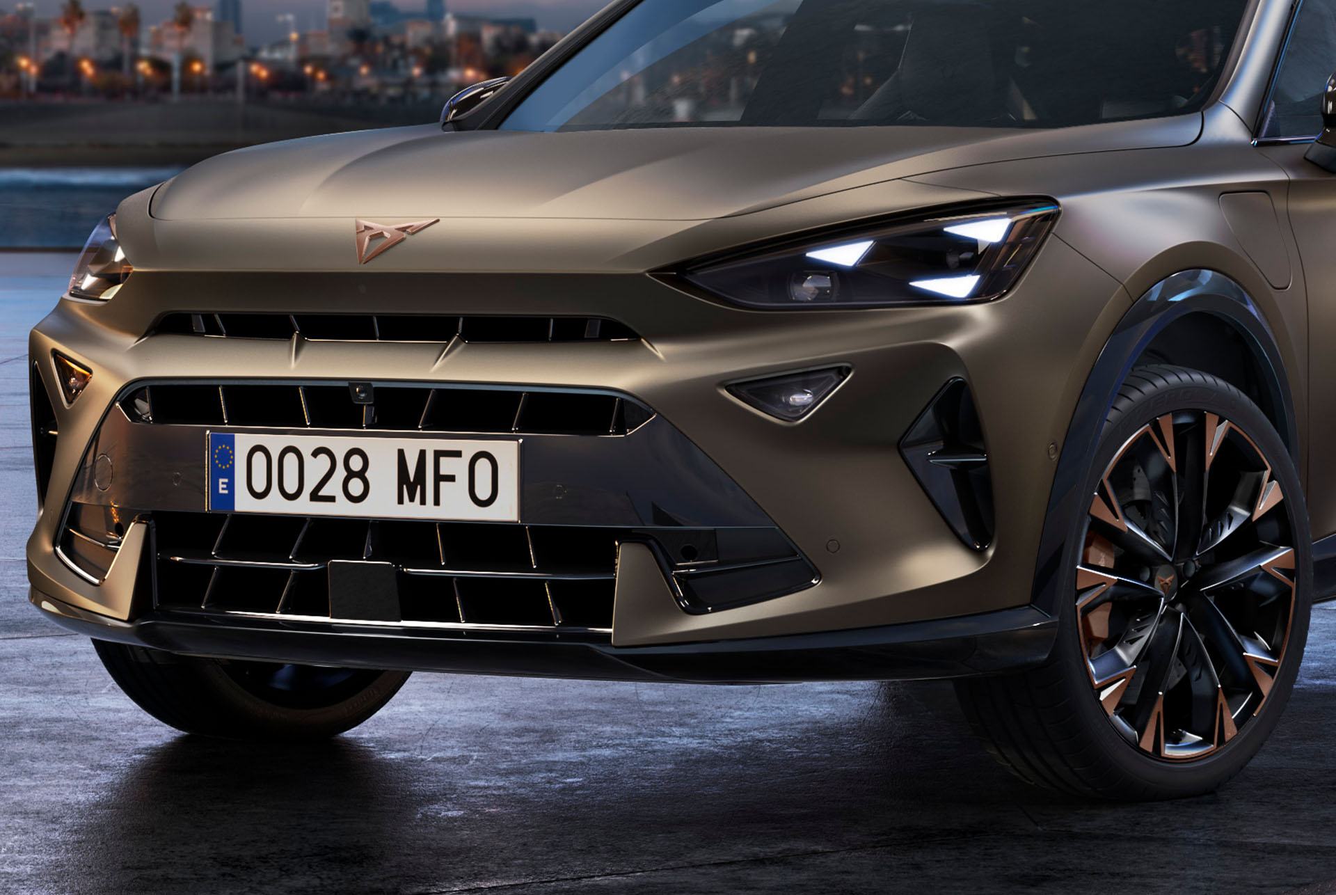 Närbild av fronten på en ny 2024-tals CUPRA Formentor CUV i brons med kopparfärgade accentfälgar, karakteristiska triangelformade framlyktor och distinkt CUPRA-logotyp.